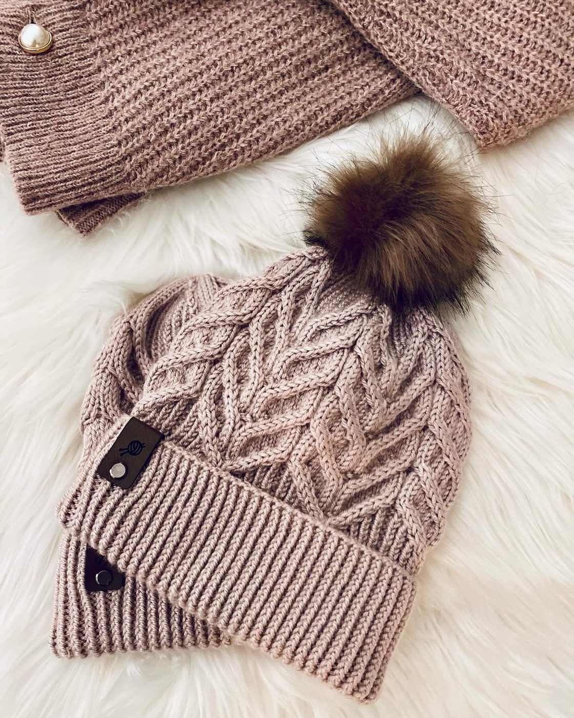 Hand-knit cable beanie in blush pink with a faux-fur pom